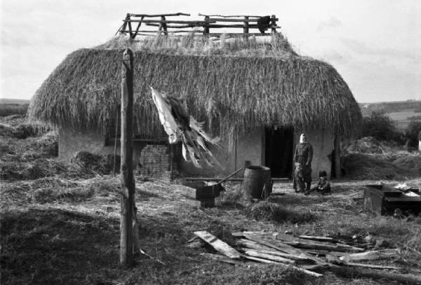 Campagna di Russia. Ucraina - verso Dnipropetrovs'k - insediamento rurale - casa con tetto in paglia - panni stesi all'aperto - donna e bambino