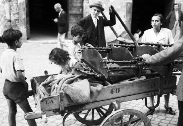 Roma - il Ghetto. Gruppo di fanciulli gioca, sotto lo sguardo di un anziano, sopra un carro merci