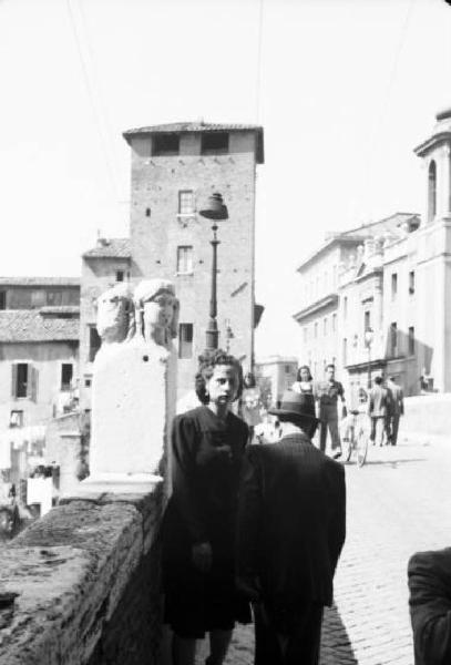 Roma - isola Tiberina. Scorcio dell'ingresso all'isoal da uno dei ponti - in primo piano una giovane donna e un anziano uomo di spalle
