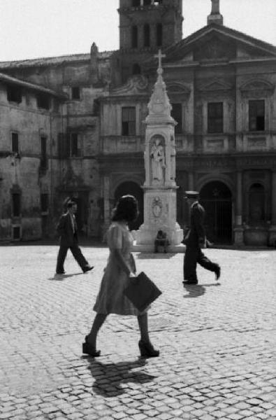 Roma - isola Tiberina. Scorcio di una piazza con l'obelisco e alcuni passanti in primo piano