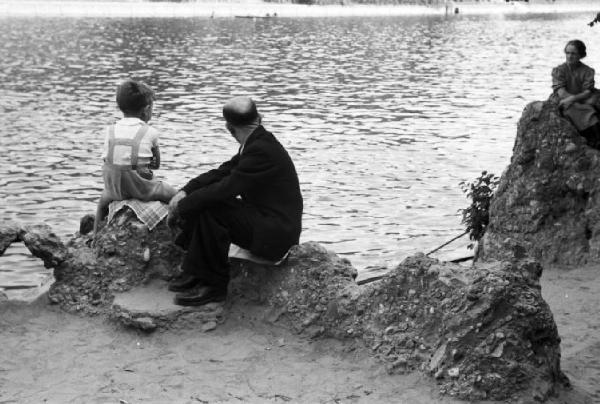 Roma - parco del Valentino. Uomo, donna e bambino seduti nei pressi di un laghetto