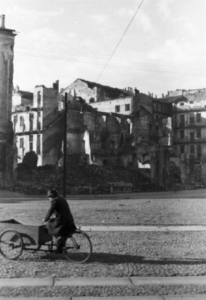 Italia Dopoguerra. Milano - piazza Vetra - Un passante in bicicletta - sullo sfondo le macerie della guerra