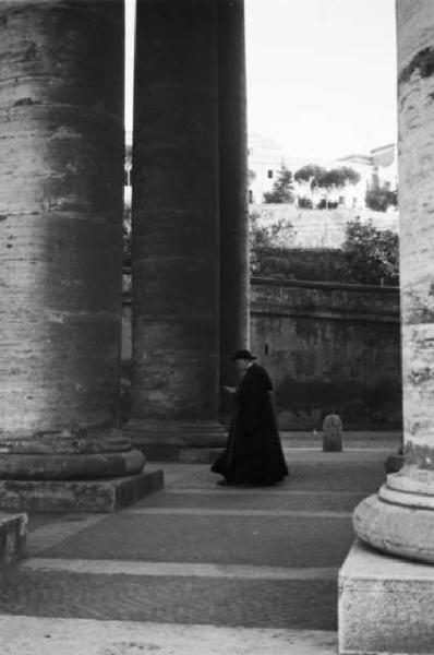 Roma. Scorcio del colonnato di Piazza San Pietro. Un prete si aggira passeggiando tra le colonne