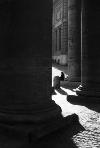 Roma. Scorcio del colonnato di Piazza San Pietro. Sullo sfondo una piccola figura siede ai piedi di una colonna