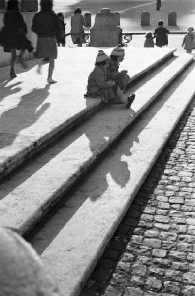 Roma. Scorcio di Piazza San Pietro. Coppia di bambine sedute sui gradini nella piazza