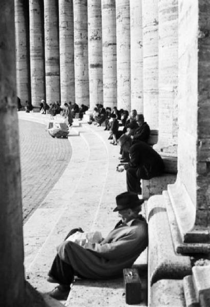 Roma. Piazza San Pietro. Scorcio del colonnato con numerose persone sedute sulla gradinata