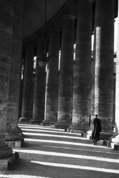 Roma. Scorcio del colonnato di Piazza San Pietro con figura maschile che si aggira passeggiando tra le colonne