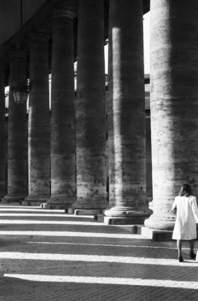 Roma. Scorcio del colonnato di Piazza San Pietro con figura femminile che si aggira passeggiando tra le colonne