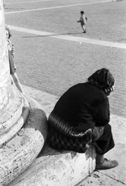 Roma. Scorcio di Piazza San Pietro. In primo piano una donna siede ai piedi di una colonna