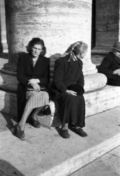 Roma. Piazza San Pietro - colonnato. In primo piano coppia di donne siede ai piedi di una colonna