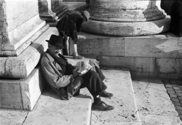 Roma. Piazza San Pietro - colonnato. In primo piano un uomo siede ai piedi di una colonna