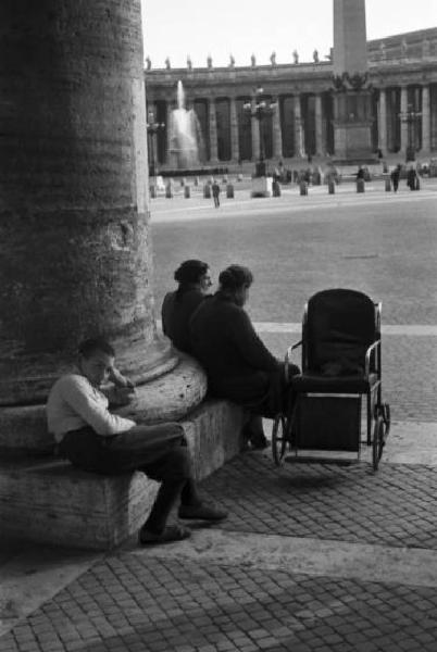 Roma. Scorcio di Piazza San Pietro. Coppia di donne e un bambino siedono ai piedi di una colonna