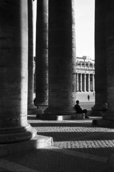 Roma. Piazza San Pietro. Scorcio del colonnato con piccola figura maschile seduta ai piedi di una colonna
