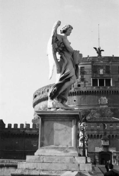 Roma. Ponte Sant'Angelo - una delle dieci statue di angeli che decorano le spallette del ponte. Sullo sfondo è visibile parte del castello in origine mausoleo