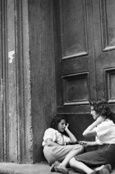 Roma - Coppia di ragazze chiacchiera seduta davanti a un portone