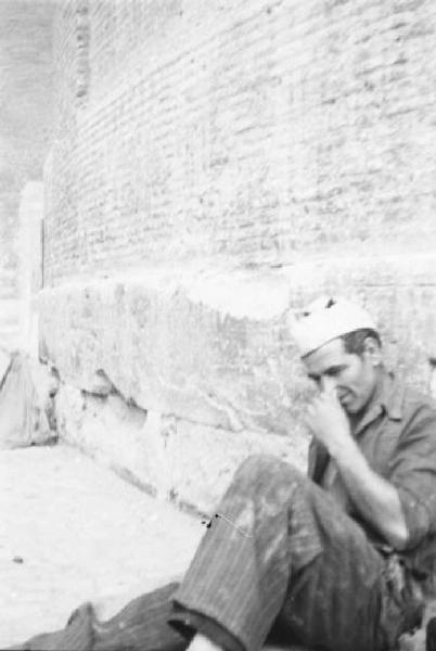 Roma - Un operaio si riposa seduto ai piedi di un muro in pietra