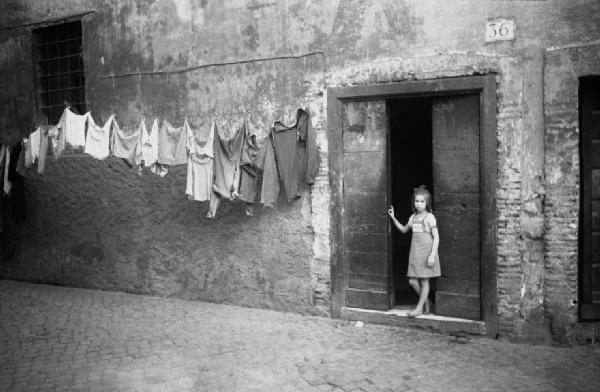 Italia Dopoguerra. Roma - Quartiere Trastevere - Bambina sulla soglia di casa - Panni stesi