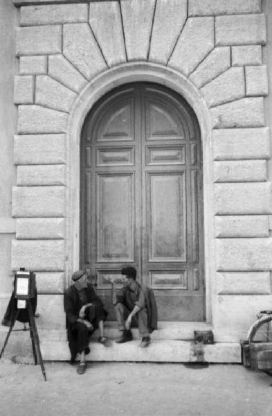 Roma - Via Conciliazione - due uomini chiacchierano seduti davanti a un portone