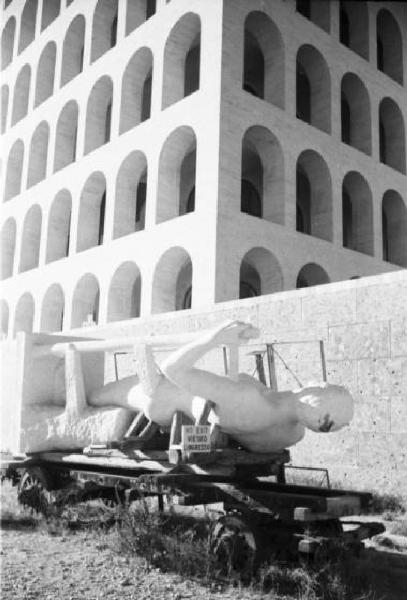 Roma - Quartiere Eur - Scorcio del Palazzo della Civiltà italiana (detto Colosseo quadrato) - statua appoggiata nell'erba in attesa di essere collocata