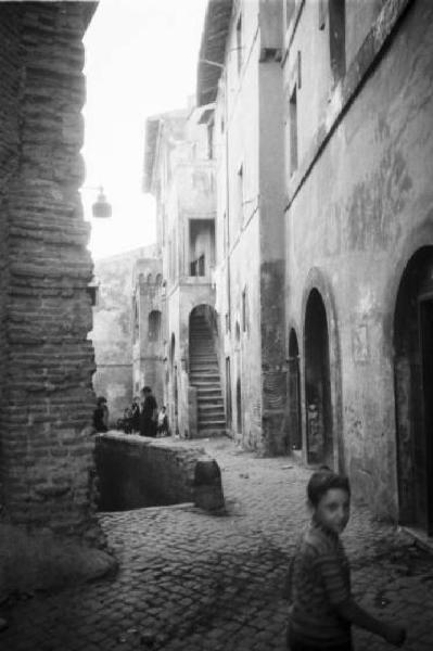 Italia Dopoguerra. Roma - Quartiere Trastevere - Scorcio di un vicolo urbano con bambino in primo piano