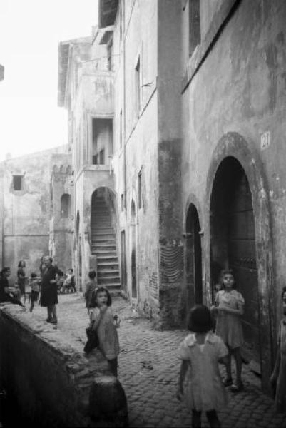 Italia Dopoguerra. Roma - Quartiere Trastevere - Scorcio di un vicolo urbano con gruppo di bambini