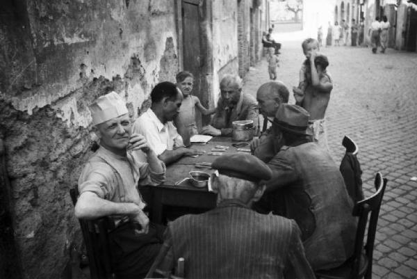 Italia Dopoguerra. Roma - Quartiere Trastevere - gruppo di uomini gioca a carte per strada