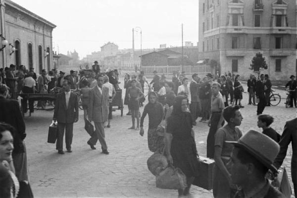 Italia Dopoguerra. Viaggio Milano-Savona. Milano, viaggiatori fuori dalla stazione di Porta Genova (?)