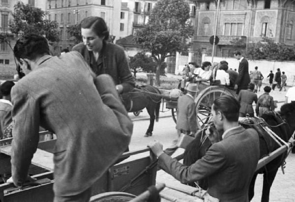 Italia Dopoguerra. Viaggio Milano-Savona. Milano, viaggiatori fuori dalla stazione di Porta Genova (?)