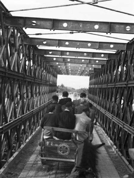 Italia Dopoguerra. Viaggio in treno Milano-Savona - Servizio di carrozze trainate da cavalli che percorre il ponte sul fiume Po