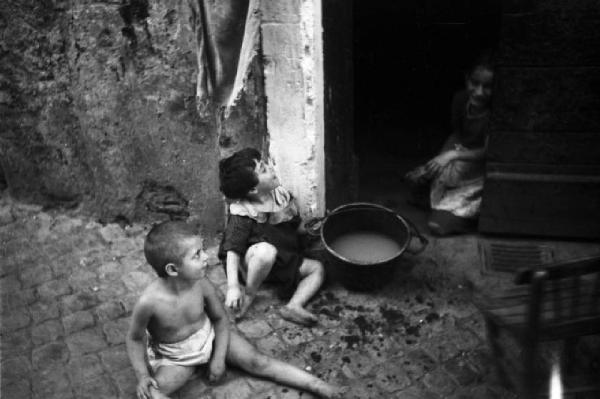 Italia Dopoguerra. Roma - Quartiere Trastevere - vita di strada - bambini seduti presso la soglia di un'abitazione