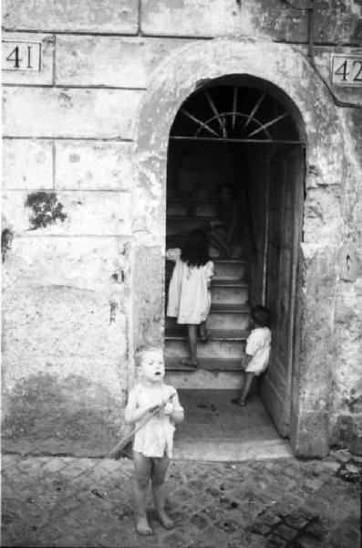 Italia Dopoguerra. Roma - Quartiere Trastevere - Scorcio di un androne con bambini sui gradini della scala