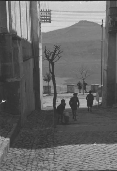 Castelgandolfo. Scene di vita quotidiana - gruppo di bambini gioca con un maialino lungo una strada della città che porta al lago di Albano