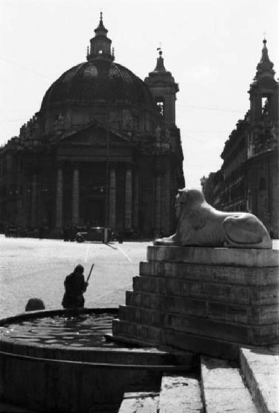 Roma. Scorcio di una delle vasche d'acqua con leone ai piedi dell'obelisco Flaminio in Piazza del Popolo, sullo sfondo è visibile la chiesa gemella di Santa Maria di Montesanto