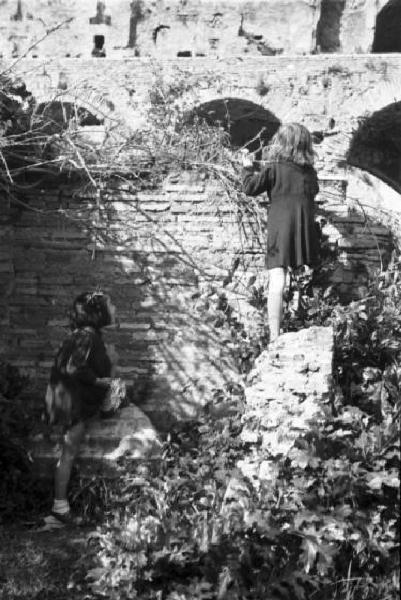 Roma. Fori Imperiali. Due bambine giocano arrampicandosi sulle rovine del foro