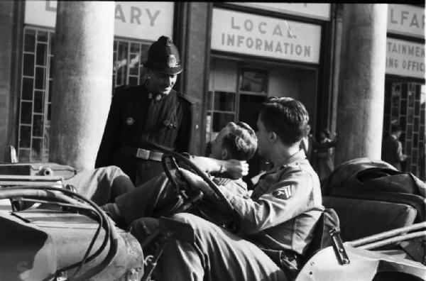 Italia Dopoguerra. Milano - Piazza del Duomo - vigile conversa con due militari su una jeep