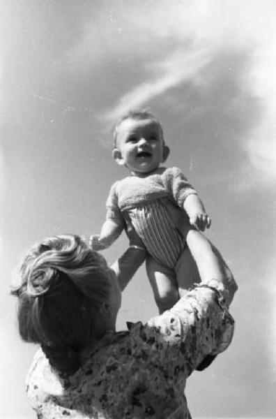 Milano - Una donna solleva verso l'alto un bambino piccolo