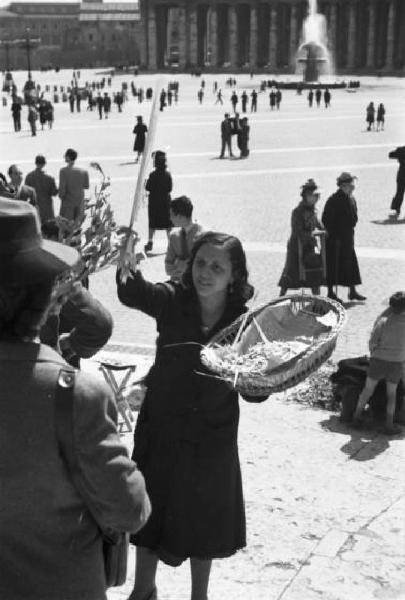 Roma. Piazza San Pietro. Una donna distribuisce ramoscelli di ulivo. Sullo sfondo la piazza con il colonnato