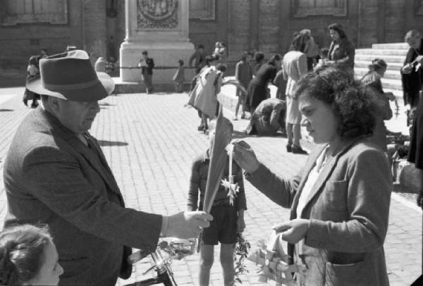 Roma. Piazza San Pietro. Un uomo riceve da una donna una croce di paglia intrecciata