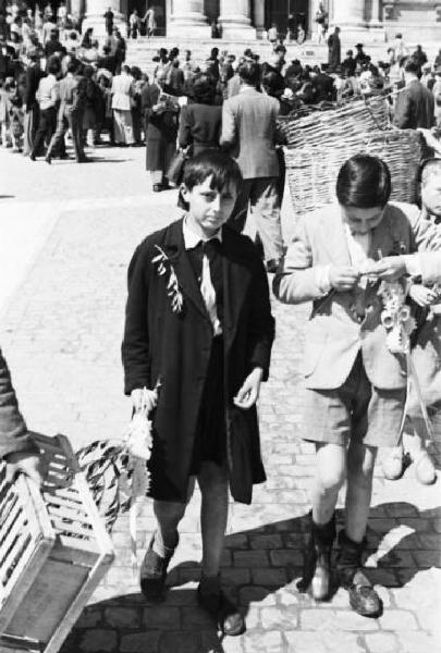 Roma. Piazza San Pietro. Coppia di bambini con ramoscelli di ulivo attraversa la piazza; sullo sfondo è raccolta una folla di pellegrini