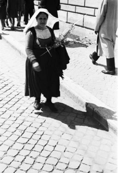 Roma. Piazza San Pietro. Una pellegrina in abiti tradizionali si avvia con in mano un ramoscello di paglia intrecciata
