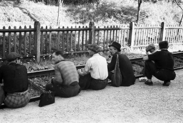 San Nicolò, boscaioli seduti  lungo il binario della ferrovia