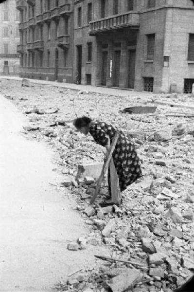 Italia Seconda Guerra Mondiale. Milano. La città dopo il bombardamento del 12 agosto 1943. Donna che raccoglie legna tra le macerie