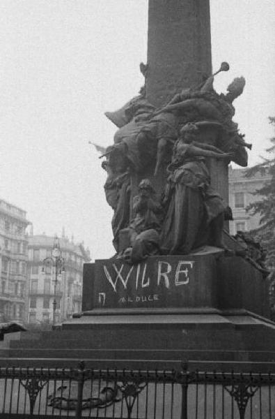 Italia Seconda Guerra Mondiale. Milano. La città dopo il bombardamento del 12 agosto 1943, il monumento di piazza del Tricolore con la scritta sul basamento "W IL RE (abbasso) IL DUCE"