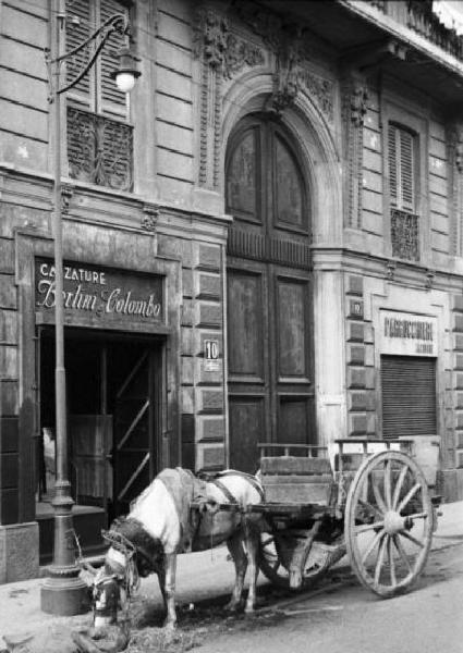 Italia Seconda Guerra Mondiale. Milano. La città dopo il bombardamento del 12 agosto 1943, un carro trainato da un cavallo in sosta davanti al portone di un palazzo