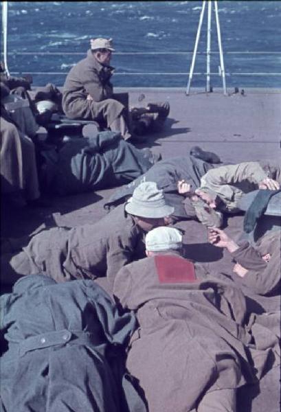 Italia Dopoguerra. Missione Casablanca. Ex prigionieri italiani seduti e sdraiati a riposare sul ponte del cacciatorpediniere Duca degli Abruzzi. Uno di essi reca cucita sulla schiena la scritta PG [prigioniero di guerra?]