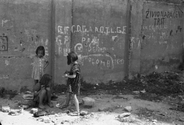 Italia Dopoguerra. Trieste - Ragazzini che giocano nei pressi di un muro ricoperto di scritte di sapore politico