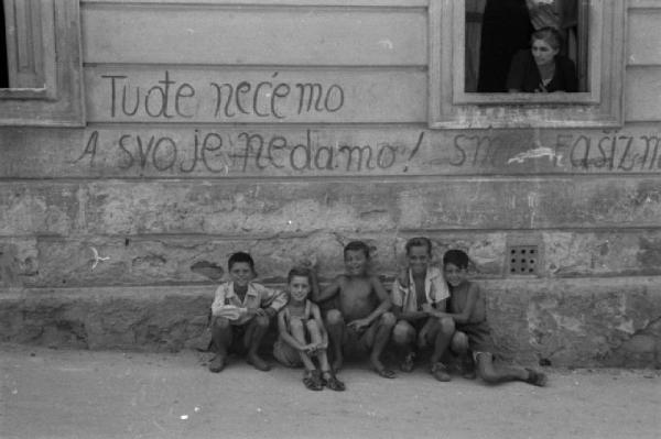 Italia Dopoguerra. Trieste - Ritratto di gruppo, ragazzini per strada nei pressi di un muro ricoperto di scritte di sapore politico inneggianti alla Jugoslavia [?]