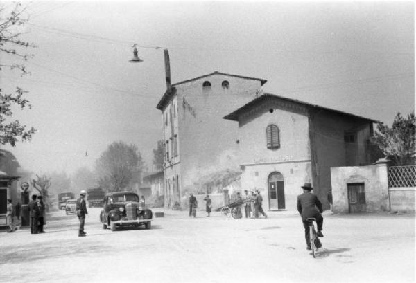 Dintorni di Pisa. Passaggio di alcune automobili di rappresentanza per il centro di un paese