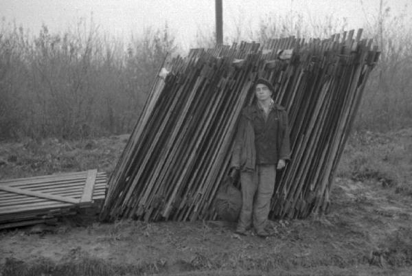 Campagna di Russia. Ucraina - Slavianka [?] - ritratto maschile - uomo posa di fronte a palizzate accatastate