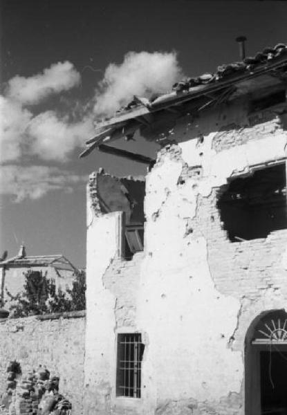 Italia Dopoguerra. Marzabotto - Il paese devastato, un edificio semidistrutto e con la facciata crivellata di colpi